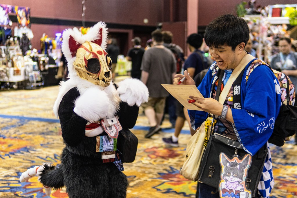 A fursuiter and an attendee sharing a moment in the Dealers Den