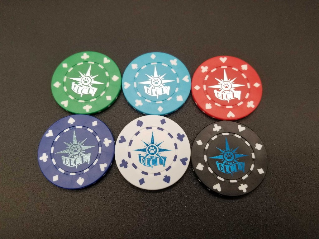 Six BLFC collectible poker chips in green, light blue, red, dark blue, white, and black, each with a paw-compass logo and suit symbols on the rim.